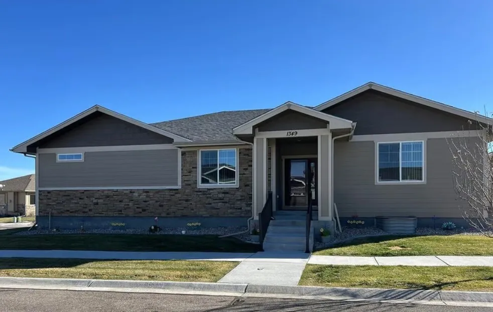 Single-story Monument home with gray siding, stonework, and a covered entry