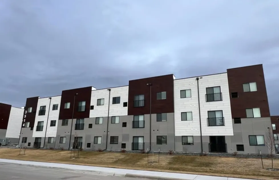 Modern multi-family building with white, gray, and brown exterior panels