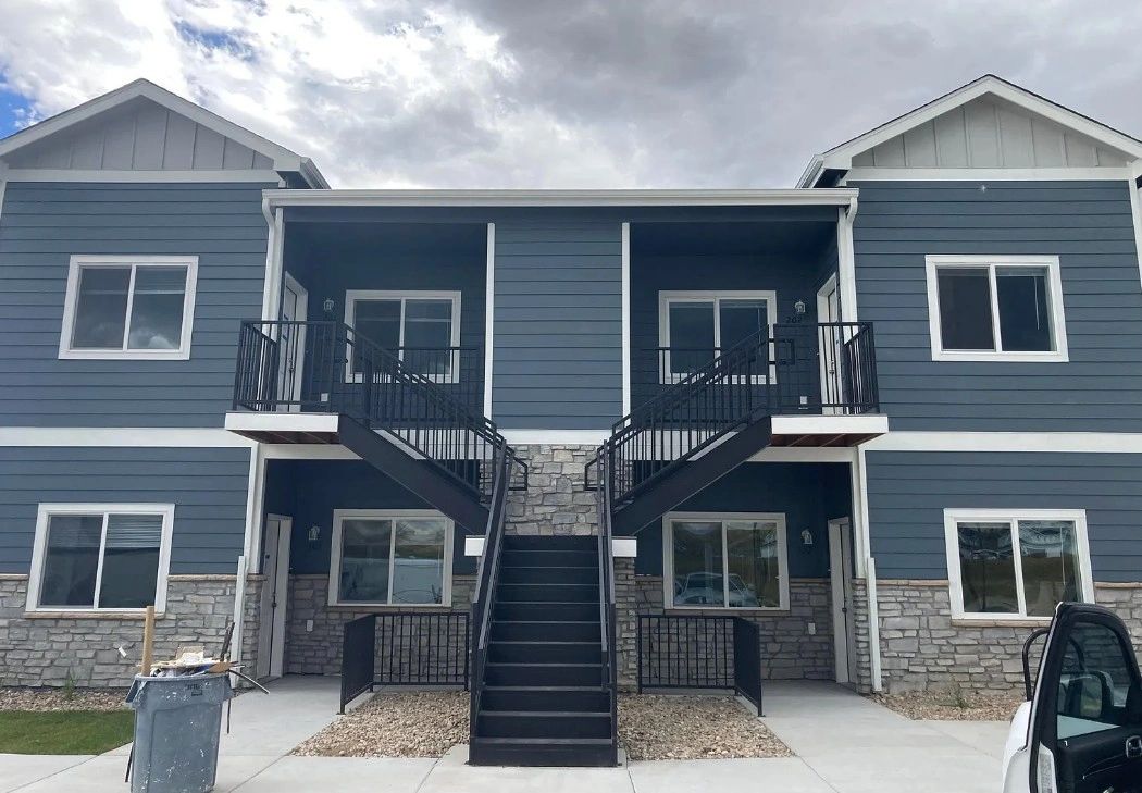 Two-story Harmony Valley multi-family building with blue siding and stonework